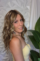 A woman with wavy blonde and brown hair wearing a pale yellow strapless top (wearing Bella by Belle Tress in color Brown Sugar Cookie R).