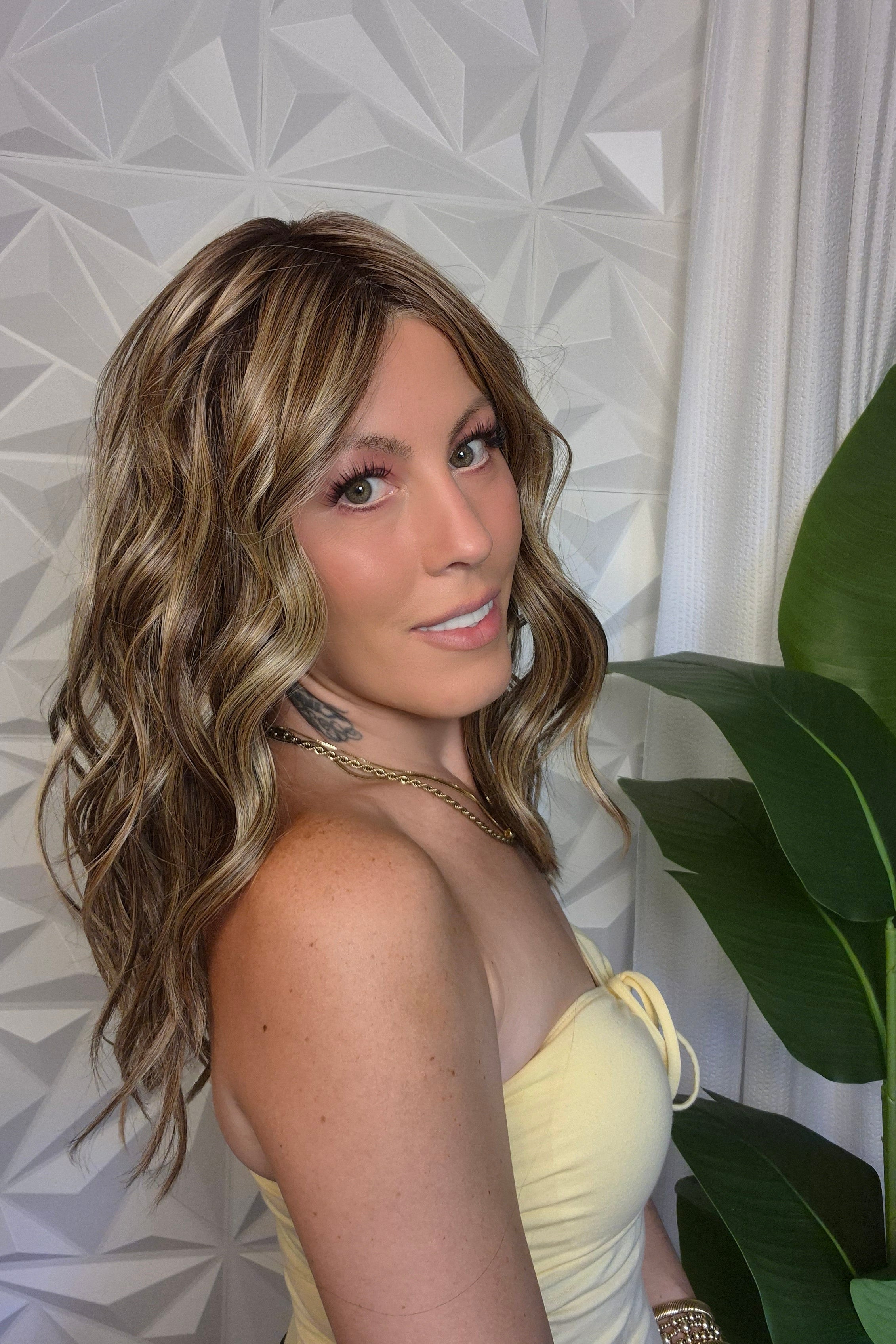 A woman with wavy blonde and brown hair wearing a pale yellow strapless top (wearing Bella by Belle Tress in color Brown Sugar Cookie R).