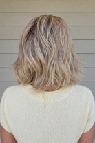 Woman with short blonde wavy wig (Rebecca by Belle Tress in color Sparkling Champagne)
