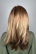 Woman wearing long layered bronde wig (Belinda Hand-Tied by Envy in Mocha Frost).