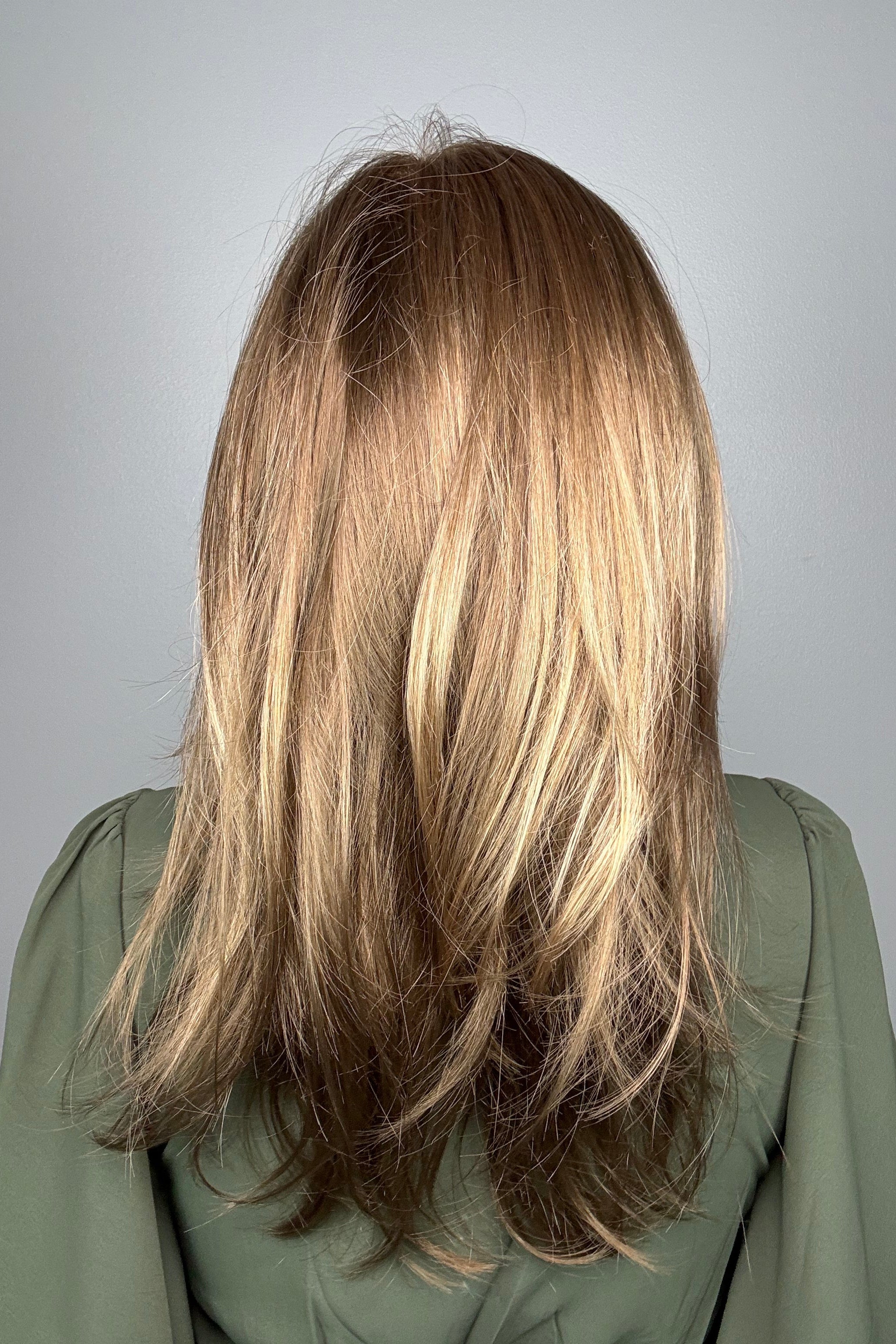 Woman wearing long layered bronde wig (Belinda Hand-Tied by Envy in Mocha Frost).