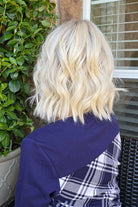 A woman wearing shoulder-length blonde wig with barrel curls (Zurich by Belle Tress in color Alpine Cream R). 