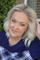 A woman wearing shoulder-length blonde wig with barrel curls (Zurich by Belle Tress in color Alpine Cream R). 