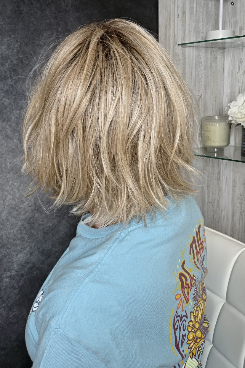 A  woman wearing chin length wispy blonde wig (Oslo by Belle Tress in color Milkshake Blonde R).