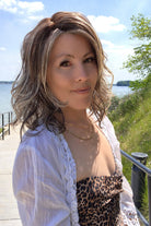Woman wearing shoulder-length curly wig (Morgan by Belle Tress in color Buttered Toast).