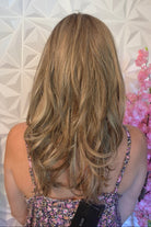 A woman with shoulder-length blonde hair and bangs wearing a floral-patterned camisole top (Marseille by Belle Tress in color Macadamia Latte R).
