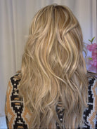 A woman with long blonde wavy wig withh bangs (Muse by Belle Tress in color Butterbeer R).