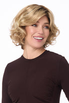 Blonde mid-length curly synthetic wig with side-swept bangs on a smiling woman.