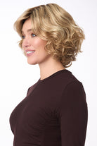 Bianca by Envy mid-length curly synthetic wig in blonde with side-swept bangs.