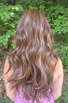 Woman wearing extra long wavy brunette wig (Bradley by PUSH Hair in color Sunlit Brunette).