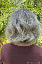 Woman wearing shoulder length curly blonde wig (Brielle by PUSH Hair in color Champagne R)