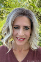 Woman wearing shoulder length curly blonde wig (Brielle by PUSH Hair in color Champagne R)