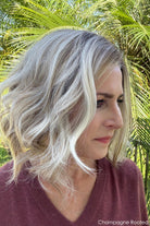 Woman wearing shoulder length curly blonde wig (Brielle by PUSH Hair in color Champagne R)
