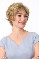 Woman wearing a short, voluminous blonde synthetic wig with soft curls and layers.