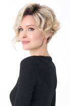 Carrisa by Envy synthetic curly blonde wig with a lace front and monofilament part on a woman.