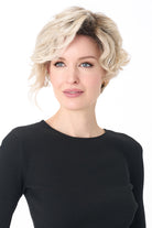 Model wearing a short, tousled blonde curly synthetic wig with a natural lace front and monofilament part.