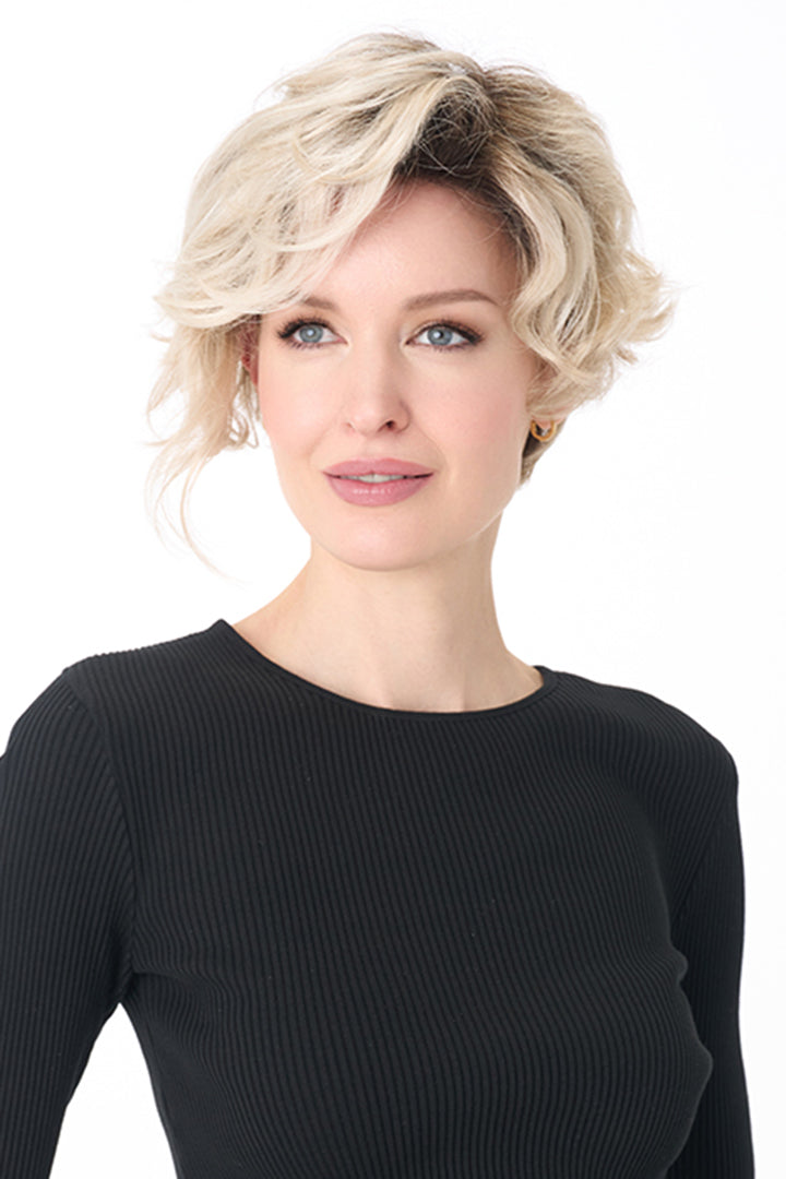 Model wearing a short, tousled blonde curly synthetic wig with a natural lace front and monofilament part.