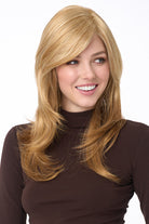 Celeste Large synthetic wig by Envy in blonde with long layers, side-swept bangs, and a natural monofilament top.