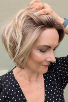 Woman wearing chin-length angled blonde bob wig (Clover by Estetica in RH18/88 RT8)