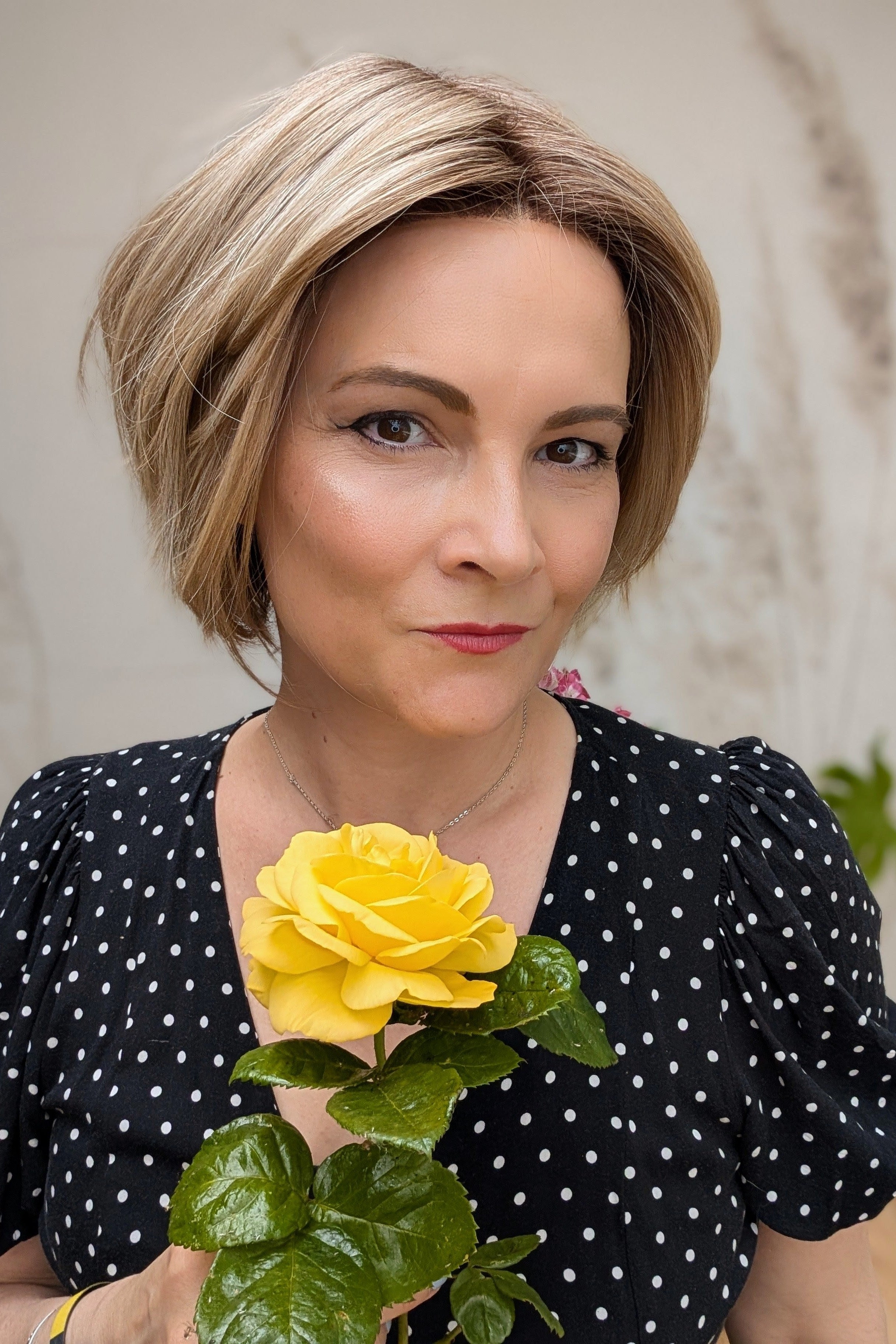 Woman wearing chin-length angled blonde bob wig (Clover by Estetica in RH18/88 RT8)
