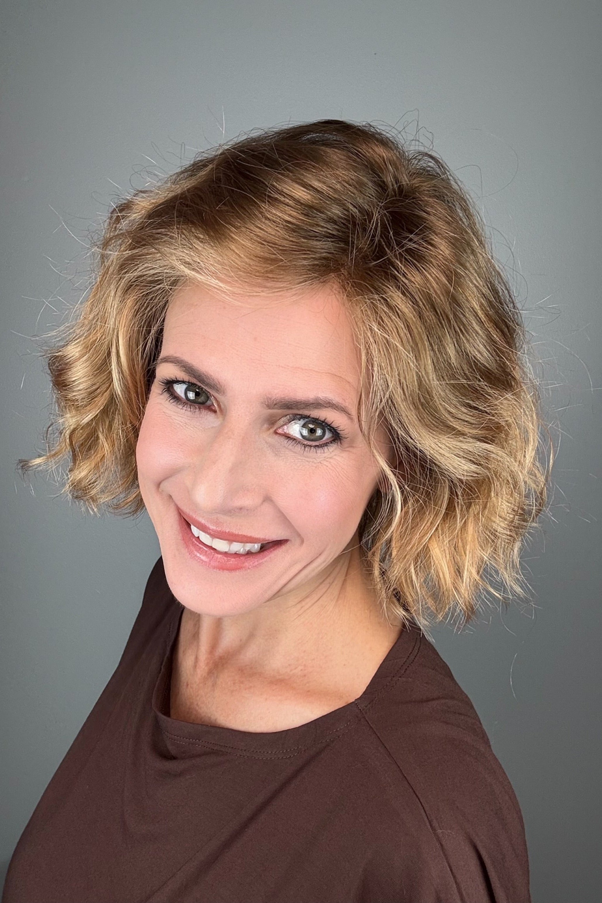 Woman wearing chin-length wavy rooted blonde bob wig (Dance by Ellen Wille in Toffee Blonde Tipped).