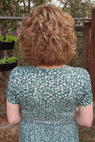 Woman wearing curly bob wig (Loop by Ellen Wille in color Tobacco R) back