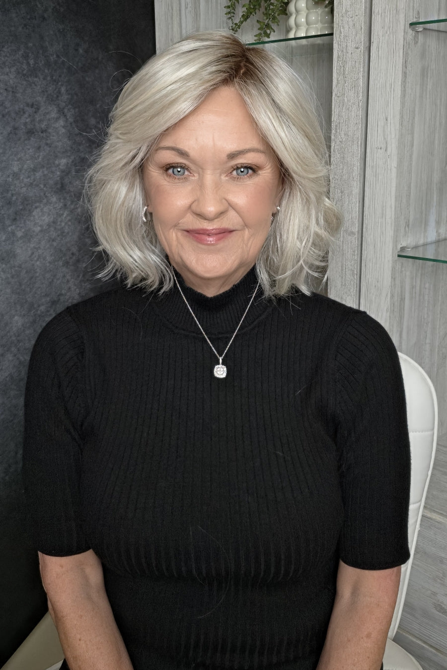 A woman with shoulder-length platinum blonde wig (Elle Mono by Ellen Wille in Silver Blonde R).