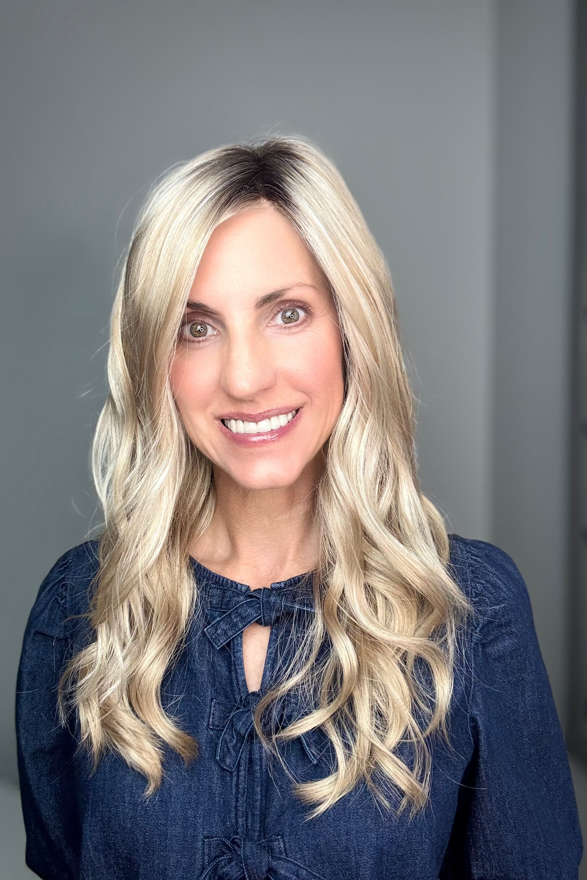 Woman with long rooted blonde wavy wig. (Maya Hand-Tied by Envy in Silky Beige).