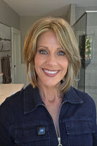 A smiling woman wearing a blonde bob wig with side bangs (Lark by Estetica in color R12/26CH). 