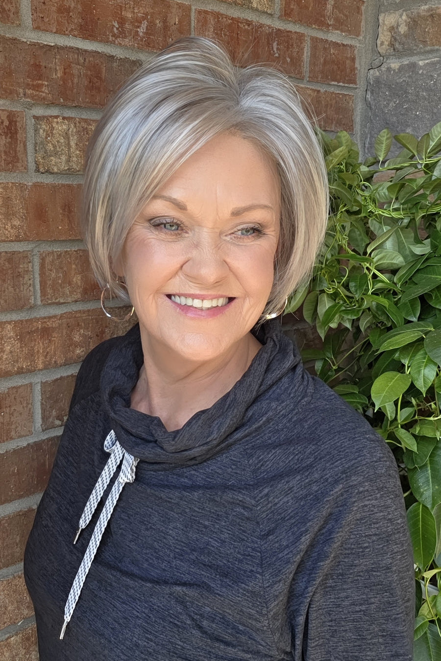 A smiling woman with short silver-gray wig (Vesper by Estetica in color R51LF60)