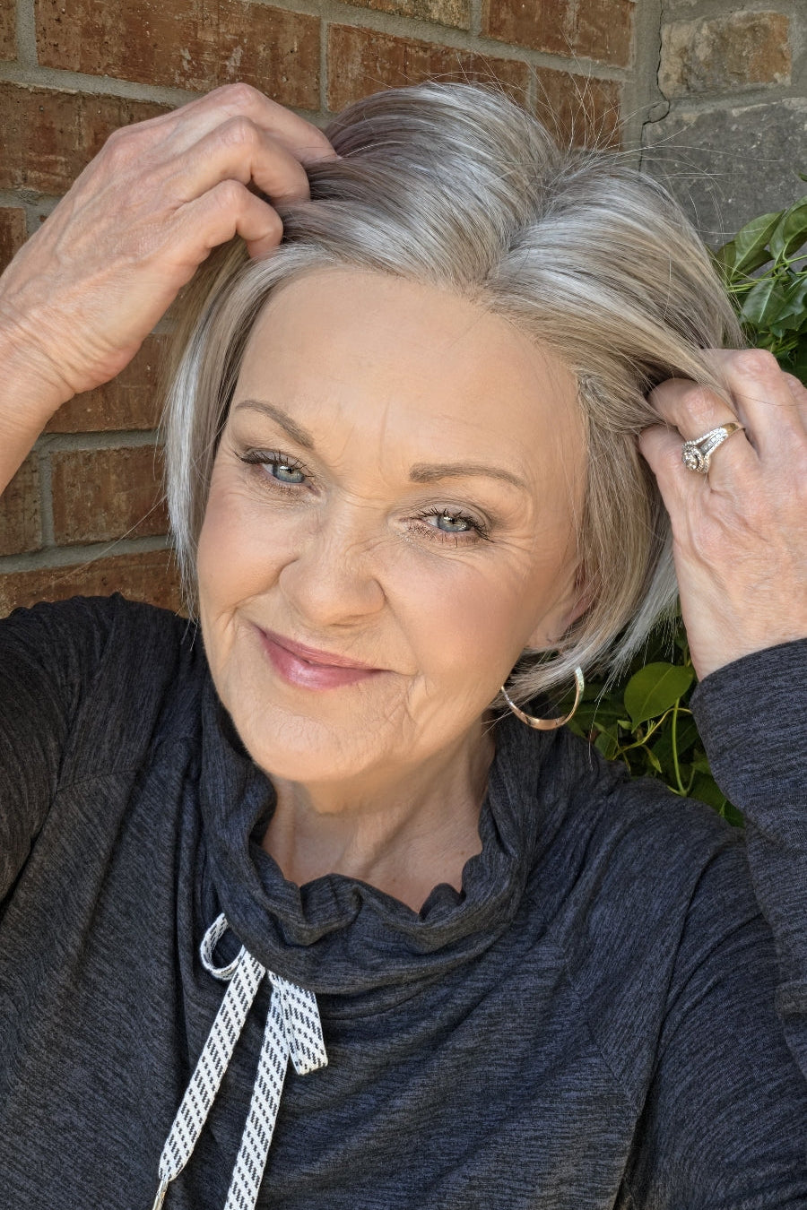 A smiling woman with short silver-gray wig (Vesper by Estetica in color R51LF60)