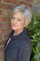A smiling woman with short silver-gray wig (Vesper by Estetica in color R51LF60)