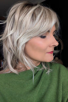 A woman with short blonde layered wig (Farrah by Belle Tress in color Butterbeer-R)