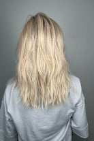 Woman wearing long layered wavy rooted blonde wig (Fenix by Estetica in Sunlit Blonde)