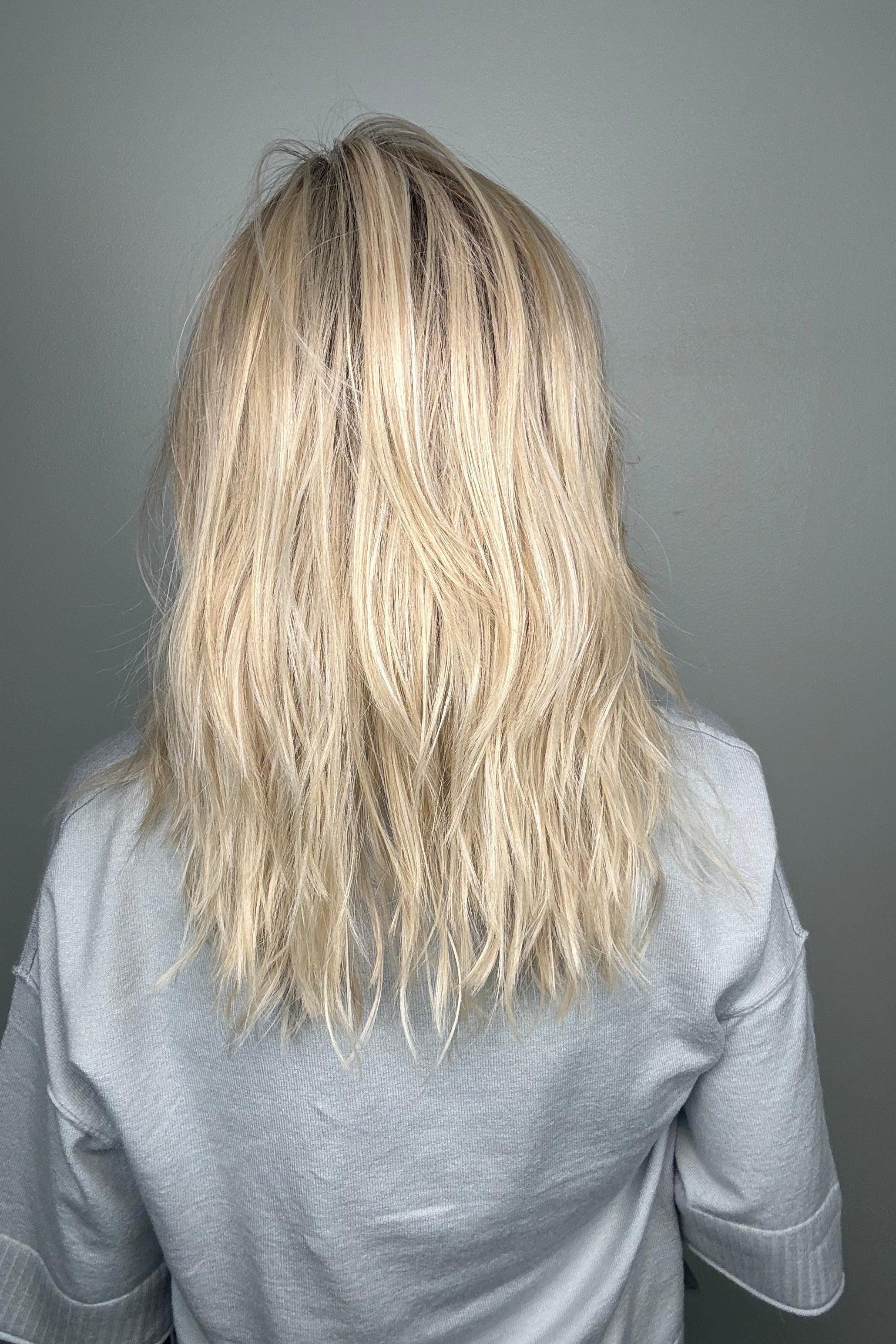 Woman wearing long layered wavy rooted blonde wig (Fenix by Estetica in Sunlit Blonde)