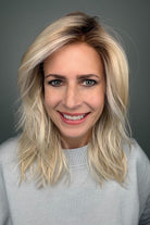 Woman wearing long layered wavy rooted blonde wig (Fenix by Estetica in Sunlit Blonde)