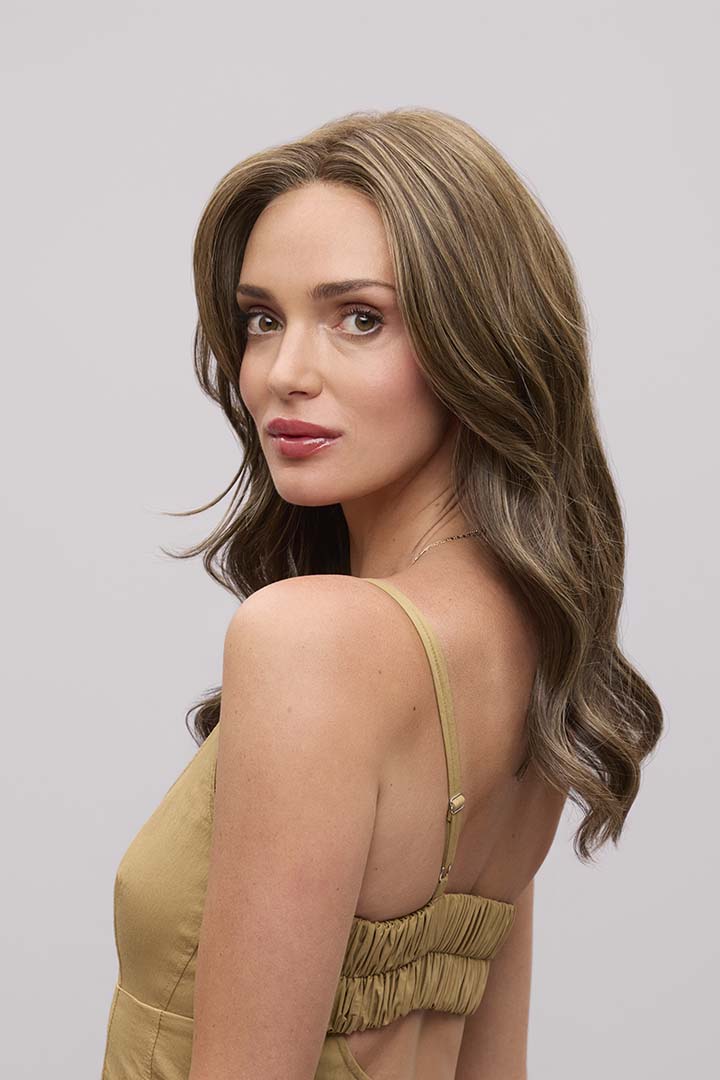 Fiona Lite heat-friendly synthetic wig with long, flowing brown waves and a natural lace front hairline.