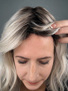 Woman wearing wavy rooted blonde wig with bangs (Frankie by Estetica in Silver Sun RT8) hairline