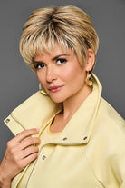 Model wearing a short, blonde, textured pixie synthetic lace front wig by Gabor with a natural hairline.