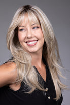 Gigi by Belle Tress long blonde synthetic wig with curtain bangs, face-framing layers, lace front, and mono top.