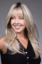 Gigi by Belle Tress long blonde layered synthetic wig with curtain bangs and a natural lace front.