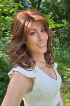 A woman wearing a shoulder-length red wig with highlighted streaks (Bouncing Belle by Gabor in Medium Red).