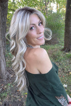 A woman with long blonde wavy wig (Gisele by Belle Tress in color Butterbeer R). 