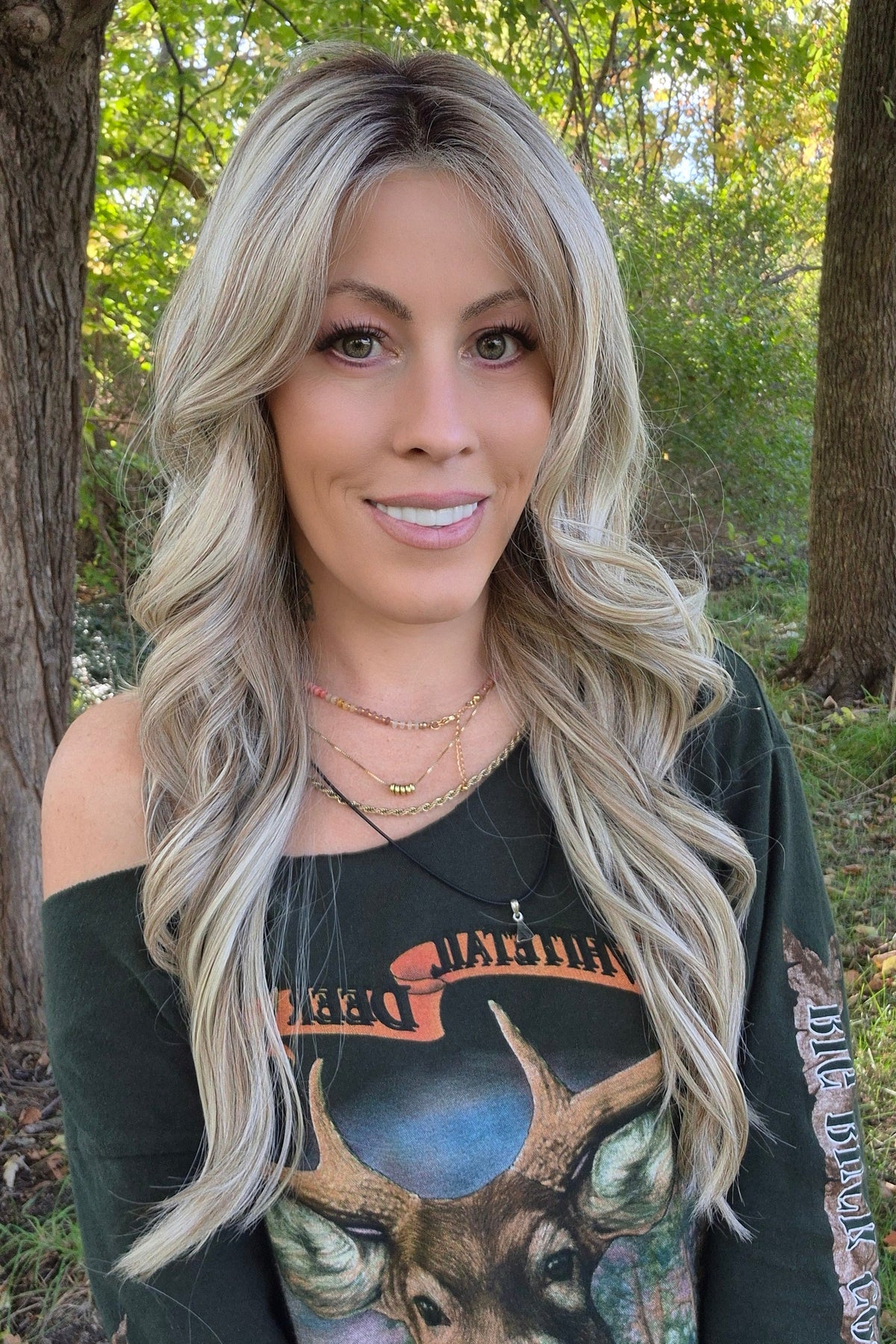 A woman with long blonde wavy wig (Gisele by Belle Tress in color Butterbeer R). 