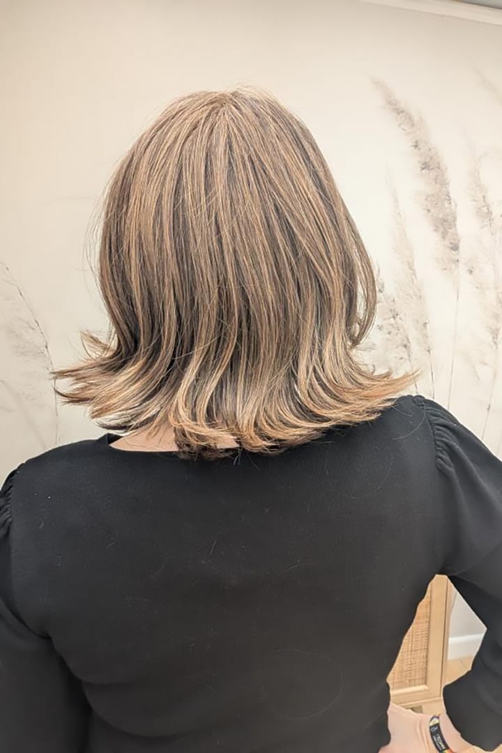 Woman with short, styled brunette wig (Harper by WigPro in Camel Brown) back
