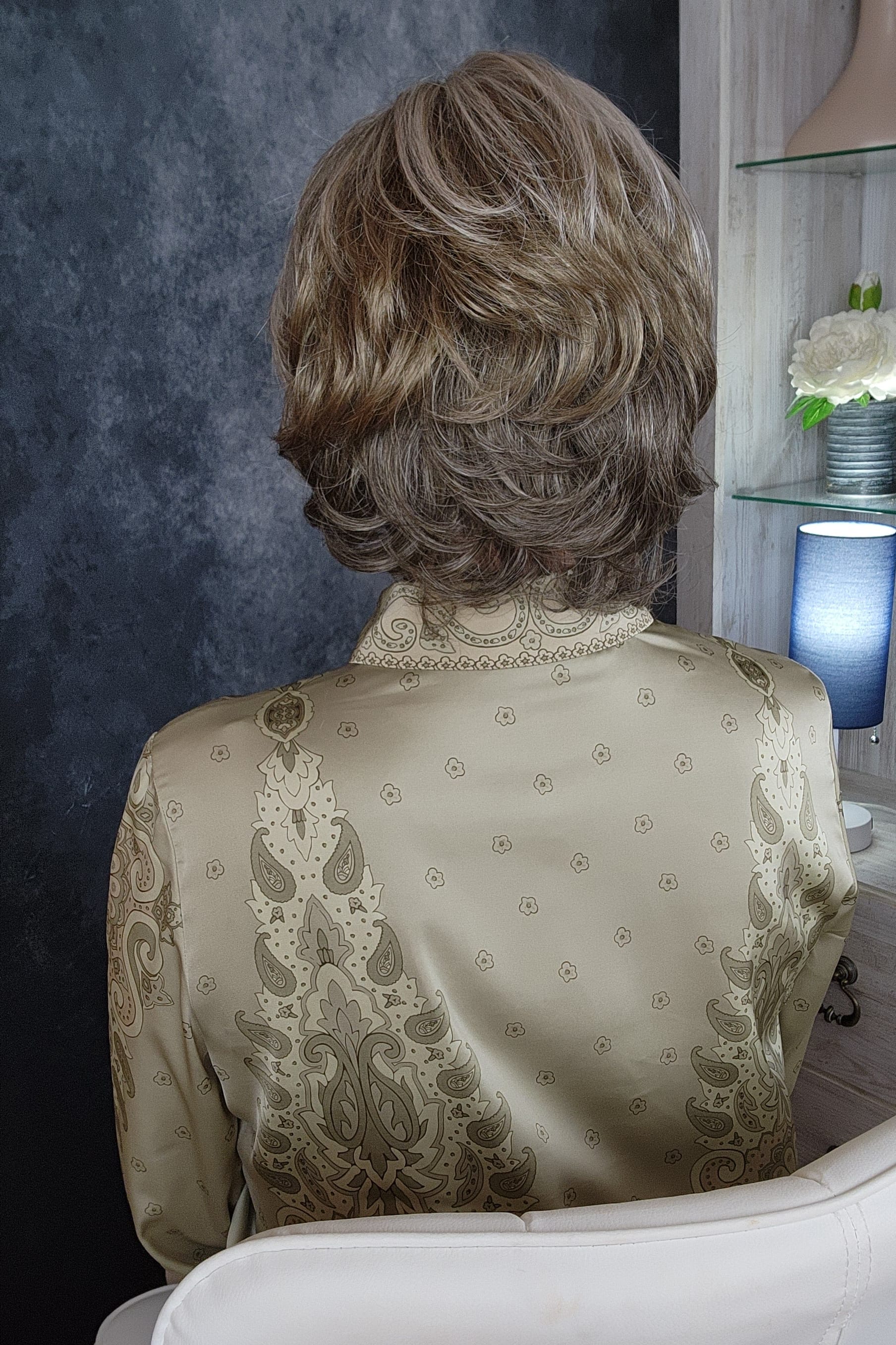 Woman wearing an ashy gray-brown bob wig with bangs (Gianna by Henry Margu in color 37)