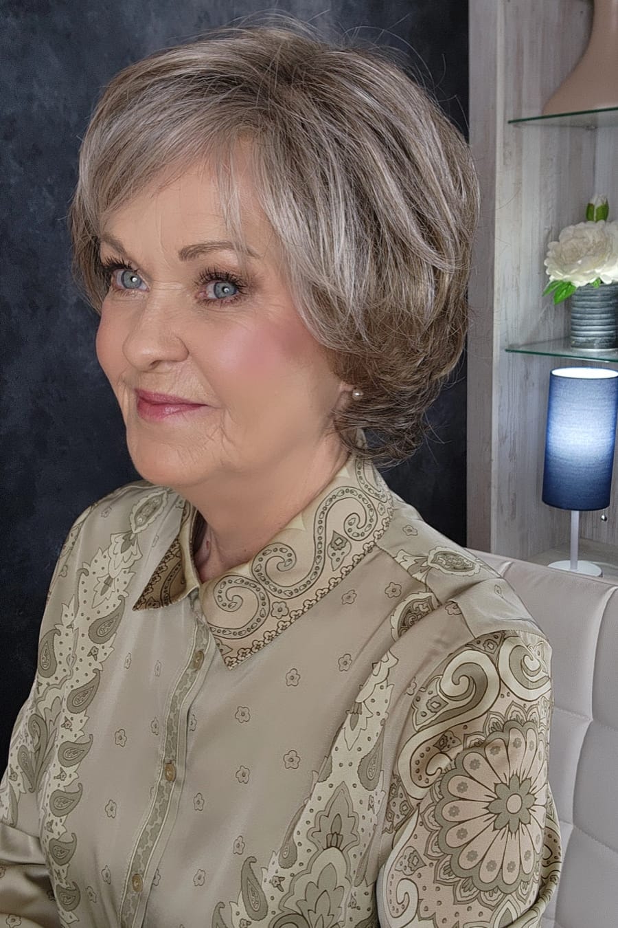 Woman wearing an ashy gray-brown bob wig with bangs (Gianna by Henry Margu in color 37)