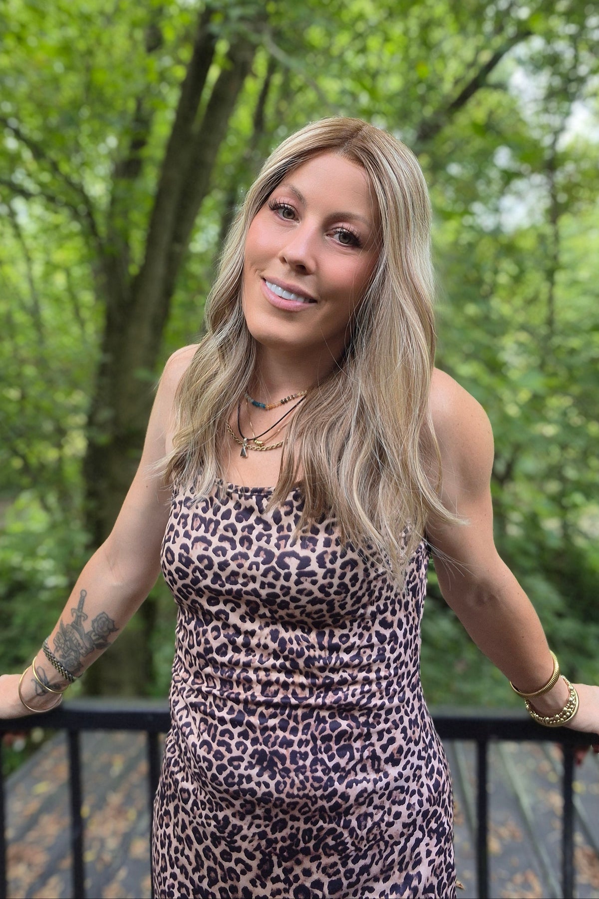 A woman with blonde wavy hair wearing a leopard print dress (Morgan by Jon Renau in Malibu Blonde)
