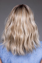 Back view of Karlie by Belle Tress, a mid-length synthetic wig with soft blonde waves and a monofilament top.
