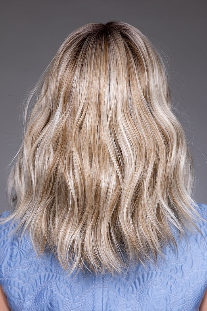 Back view of Karlie by Belle Tress, a mid-length synthetic wig with soft blonde waves and a monofilament top.